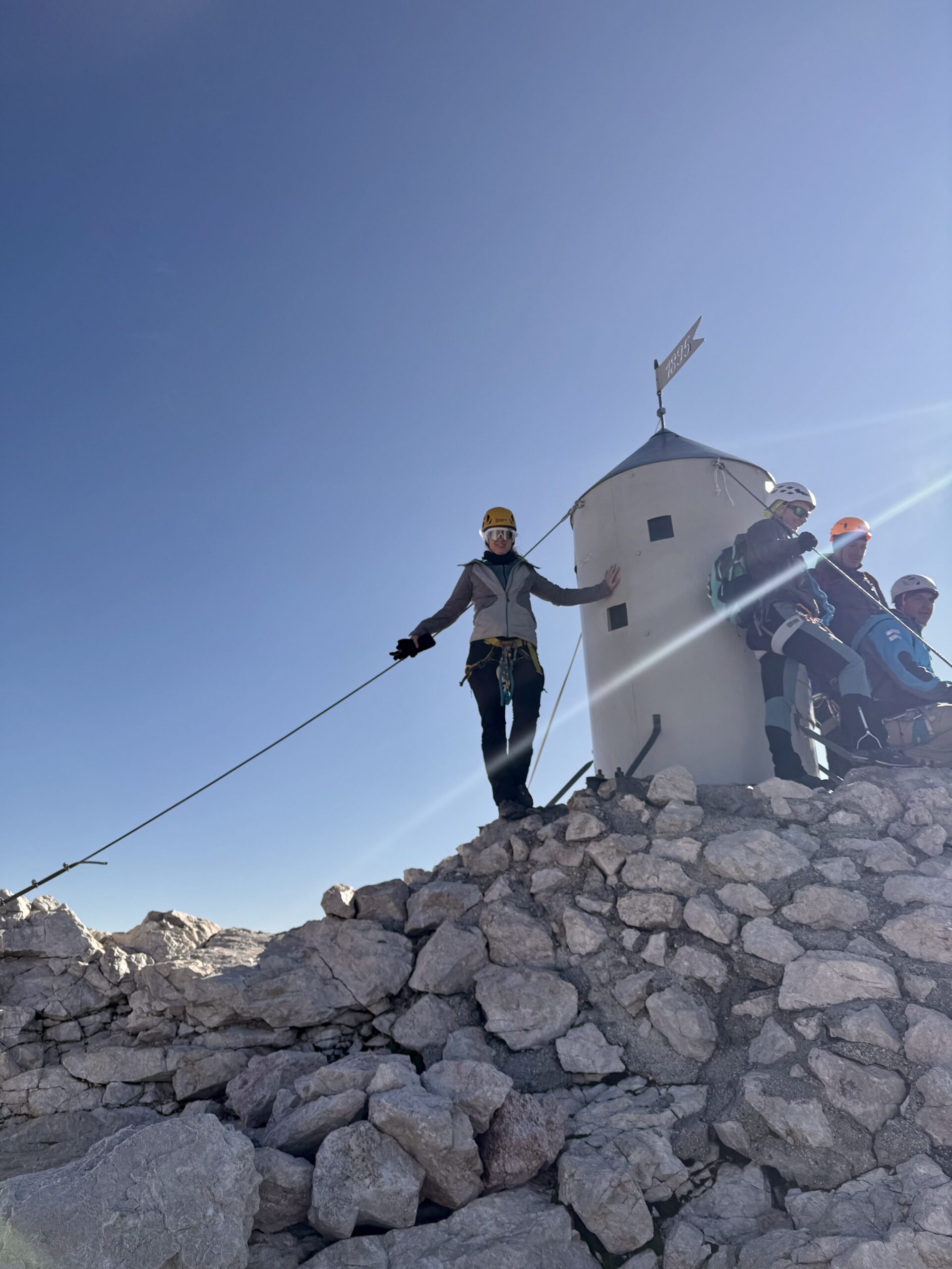 Hiker beside Aljaž Tower at the summit of Mount Triglav